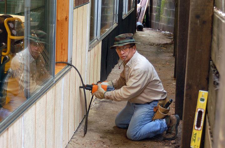M10-30.JPG - Leland uses a nail gun to fasten new siding in place.  (Mar 2010)