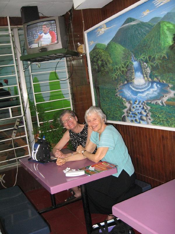 MK049.jpg - Linda and Arlene and group enjoyed fruit drinks after a visit to the US Embassy. Note the rightwing ARENA supporter on the TV.  His shirt celebrates DAubisson, who organized Fr. Romeros murder in  1980.
