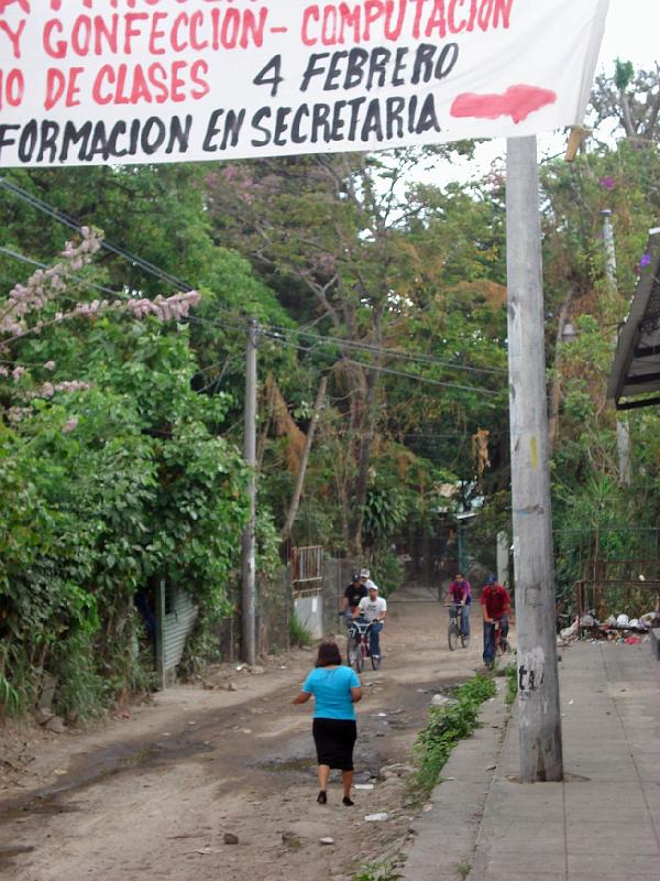 S084.jpg - Sign outside the El Despertar Catholic Center announces classes in sewing and tailoring, computers, secretarial skills, etc.